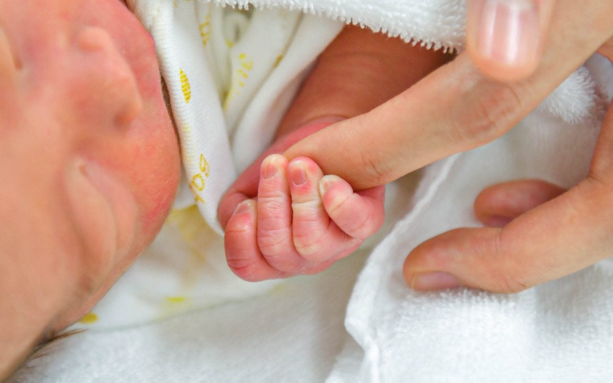 γυναίκα που είχε πρόβλημα με την γονιμότητα κρατά το χέρι του μωρού της
