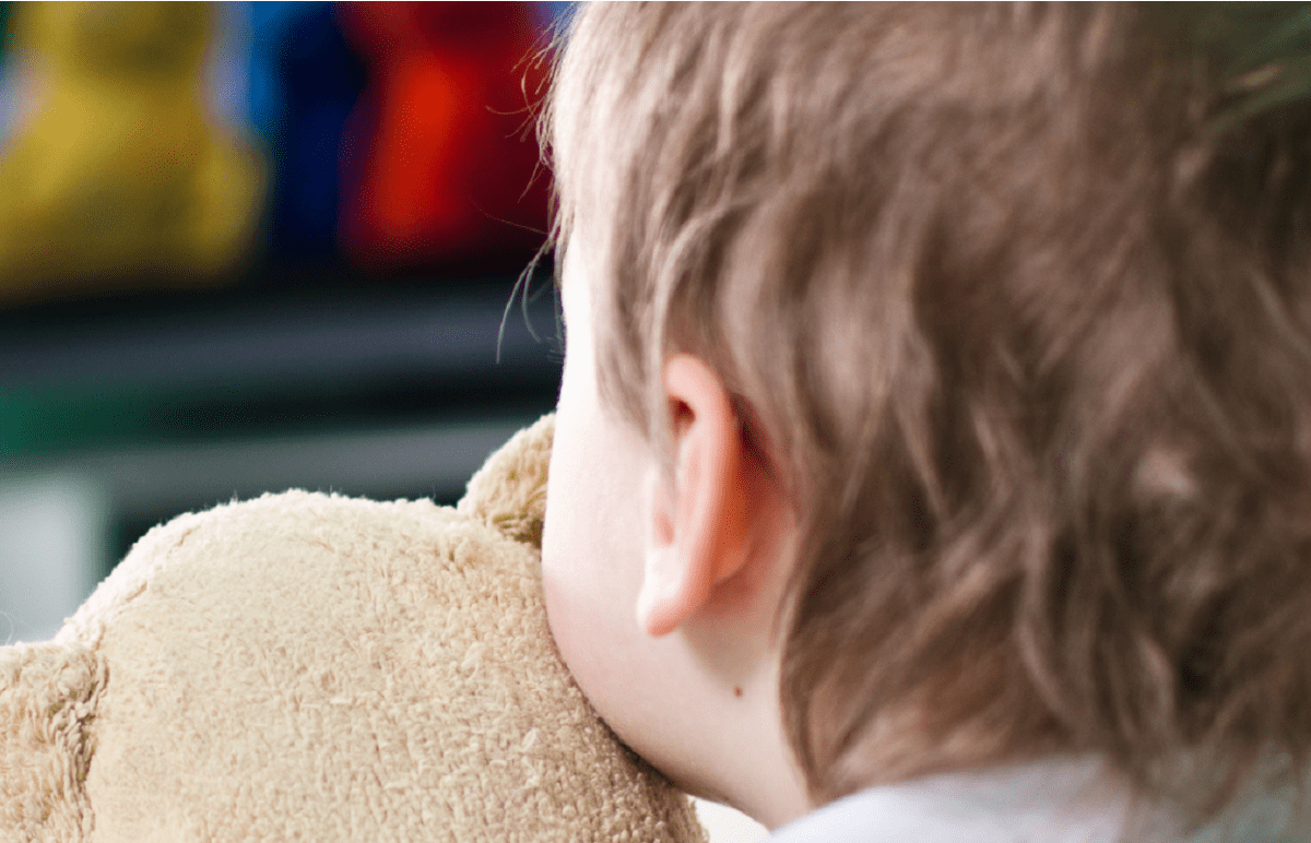 ένα μωρό βλέπει τηλεόραση και κρατά ένα αρκουδάκι