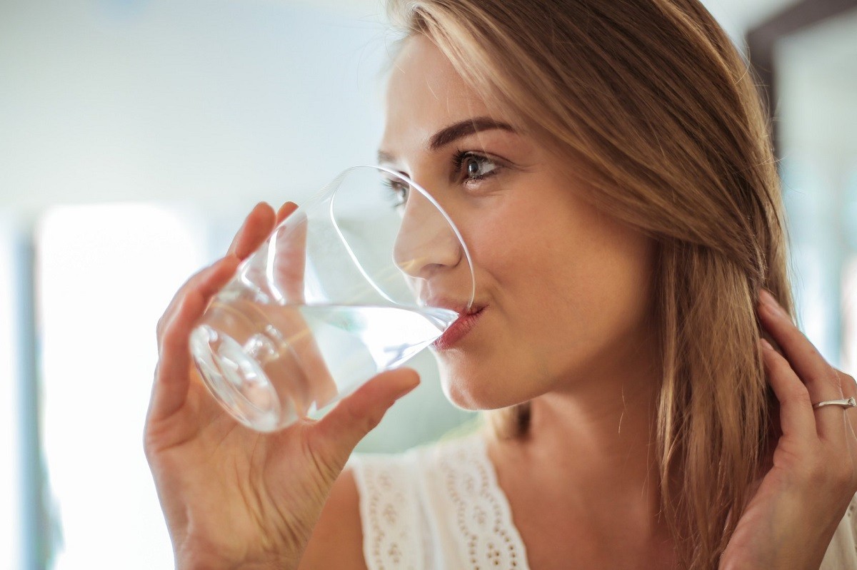 νεαρη γυναίκα πίνει νερό σε ποτήρι