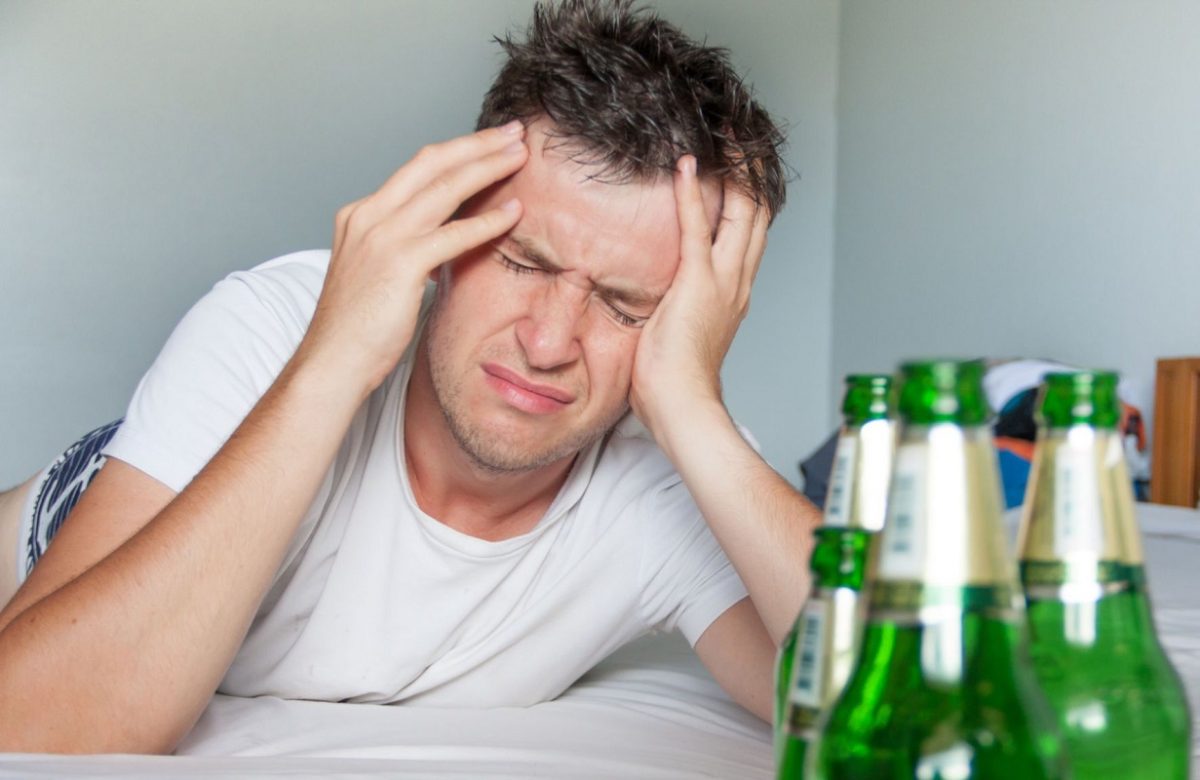 άντρας ξυπνά με hangover μπροστά από μπουκάλια μπίρας