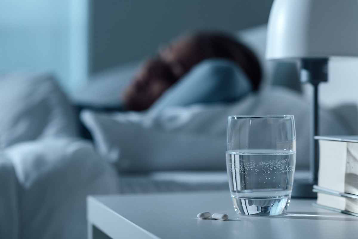 γυναίκα κοιμάται με ένα ποτήρι νερό στο κομοδίνο της