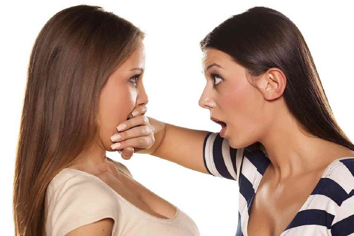 δυο γυναίκες που η μια κλείνει το στόμα της άλλης