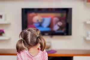 ένα παιδί, μικρό κοριτσάκι, βλέπει τηλεόραση