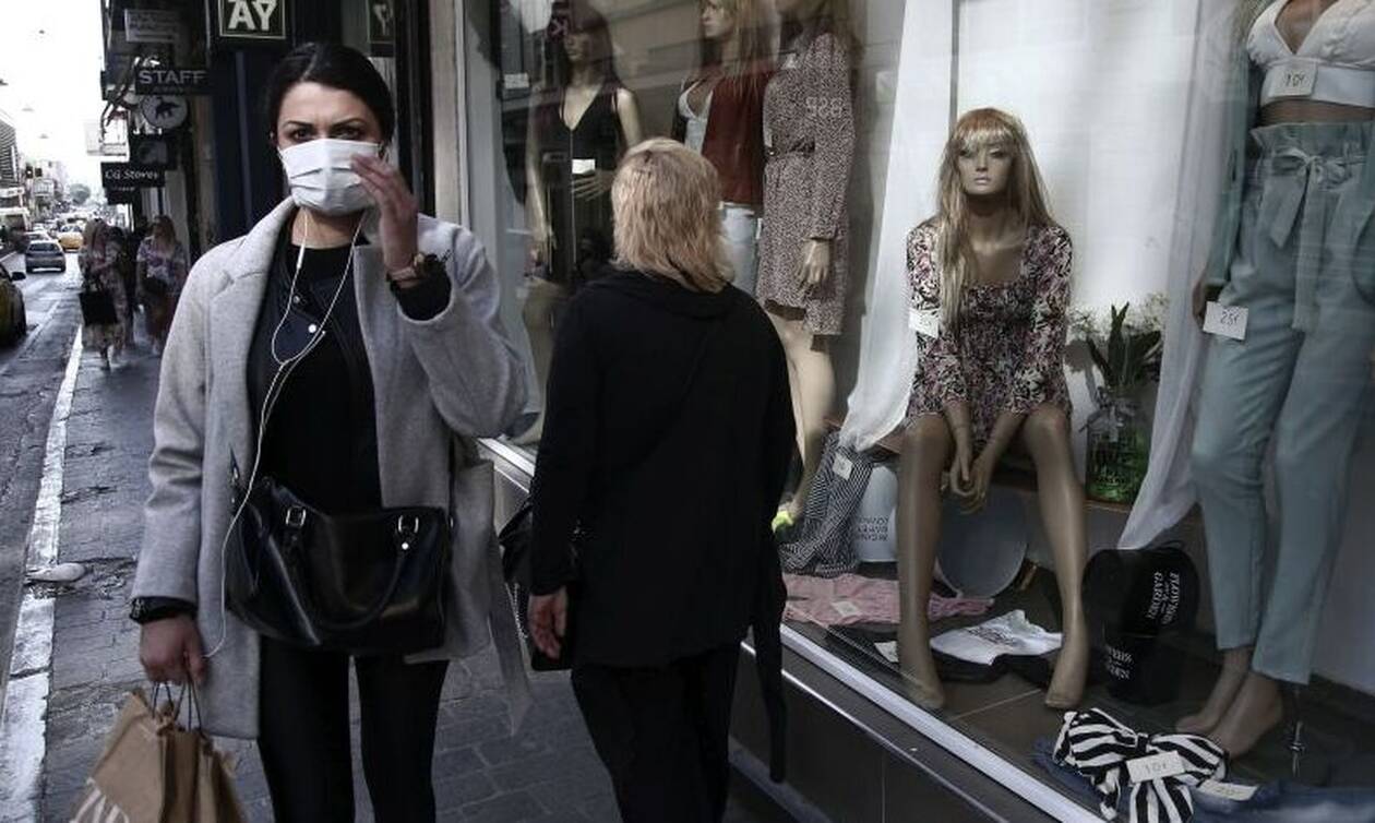 Γυναίκα με μάσκα μπροστά από βιτρίνα