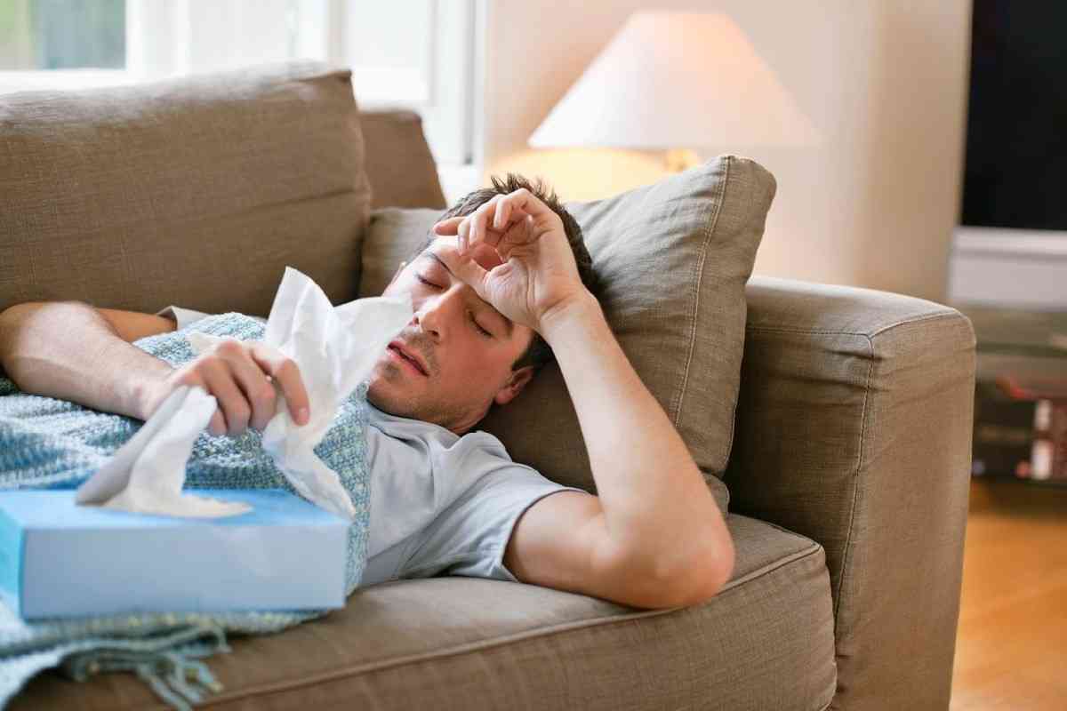 άνδρας με γρίπη ξαπλωμένος στον καναπέ που δεν μπορεί να τον πάρει ο ύπνος
