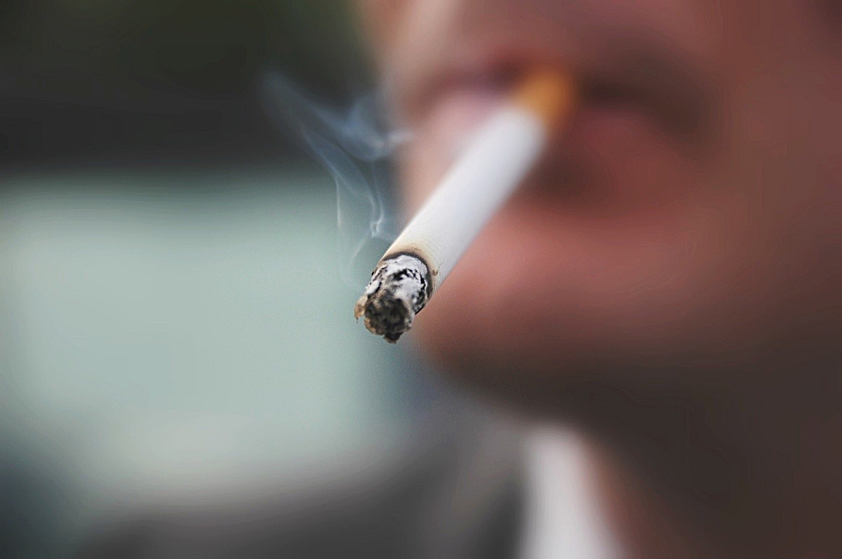 άνδρας με αναμένο τσιγάρο στο στόμα απολαμβάνει το κάπνισμα