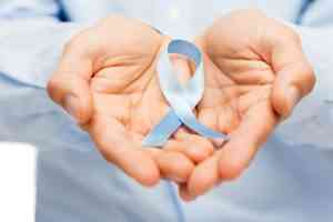 άνδρικό χέρι κρατά μπλέ κορδέλα για καρκίνο του προστάτη