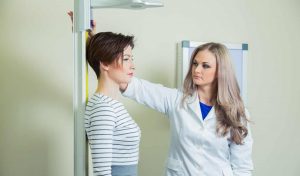 Γιατρός μετράει το ύψος μιας νεαρής γυναίκας