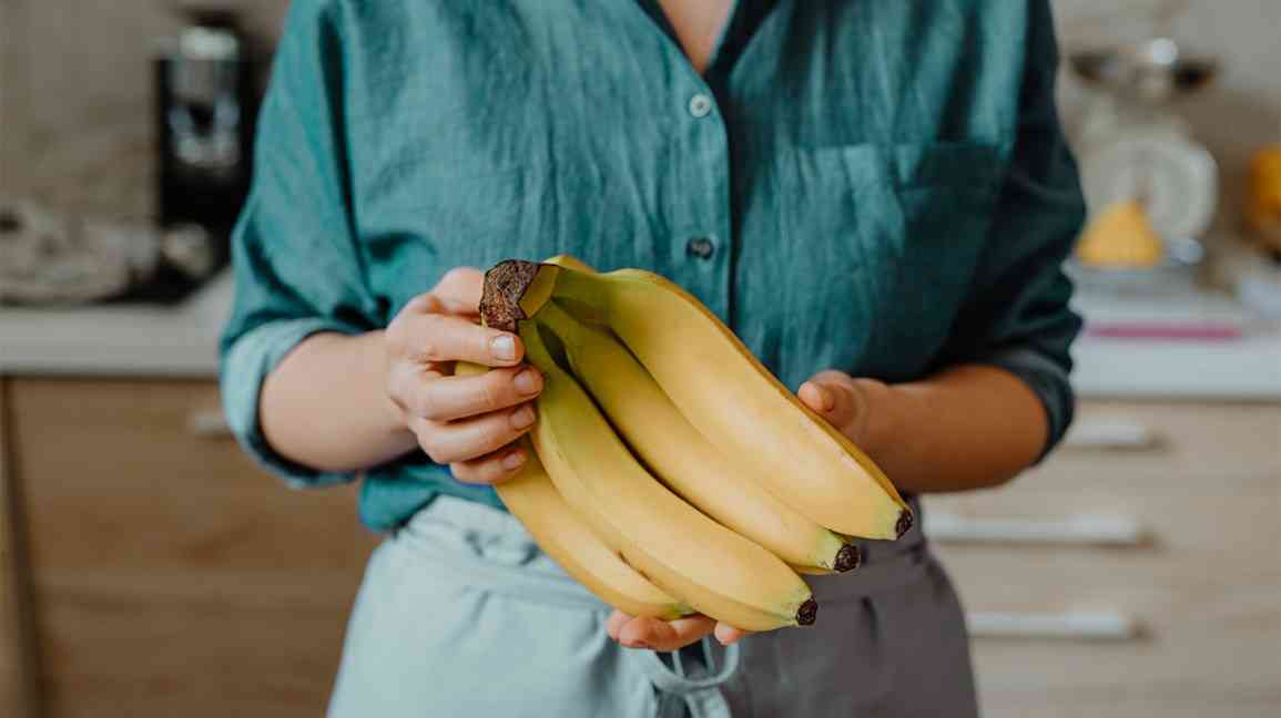 γυναίκα κρατάει ένα τσαμπί μπανάνες